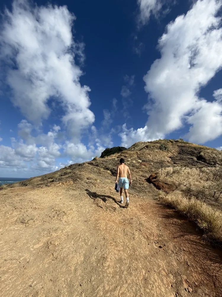 Hiking up a dry ridge under big clouds